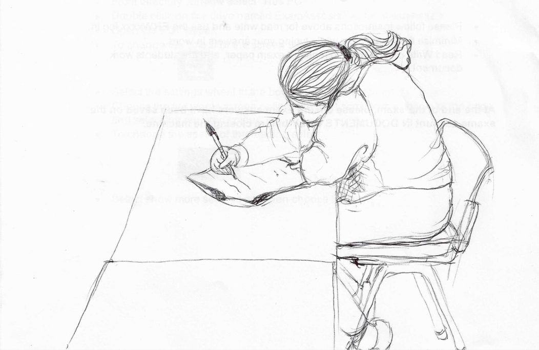 Person sitting at a table, writing in a notebook with a pen.
